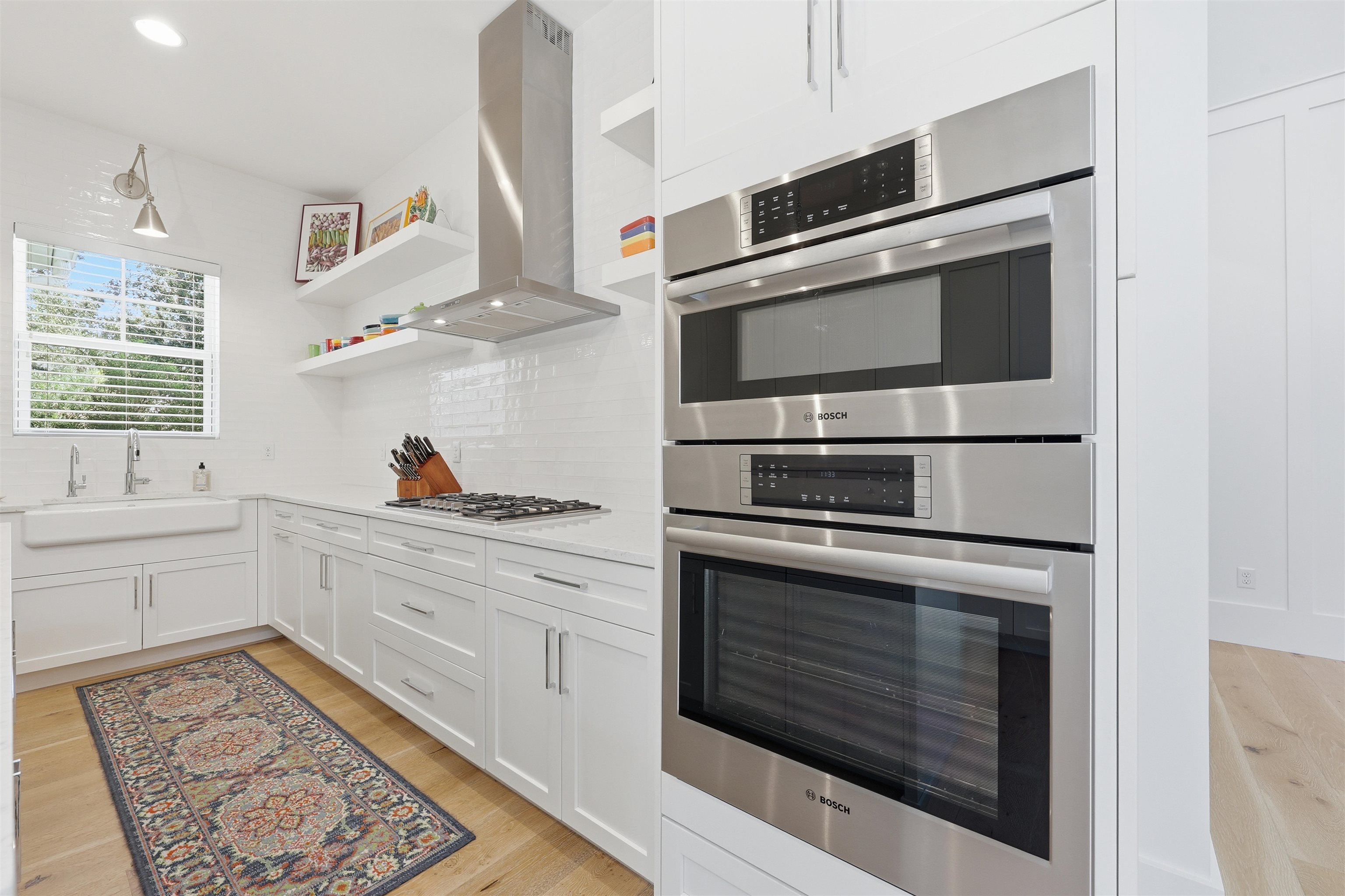 66 Ridgeway Road St. Augustine, FL 32080 - Photo 14 of 53 Kitchen featuring stainless steel appliances, white cabinetry, open shelves, backsplash, and exhaust hood