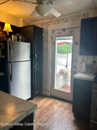 a view of a refrigerator in kitchen and an empty room