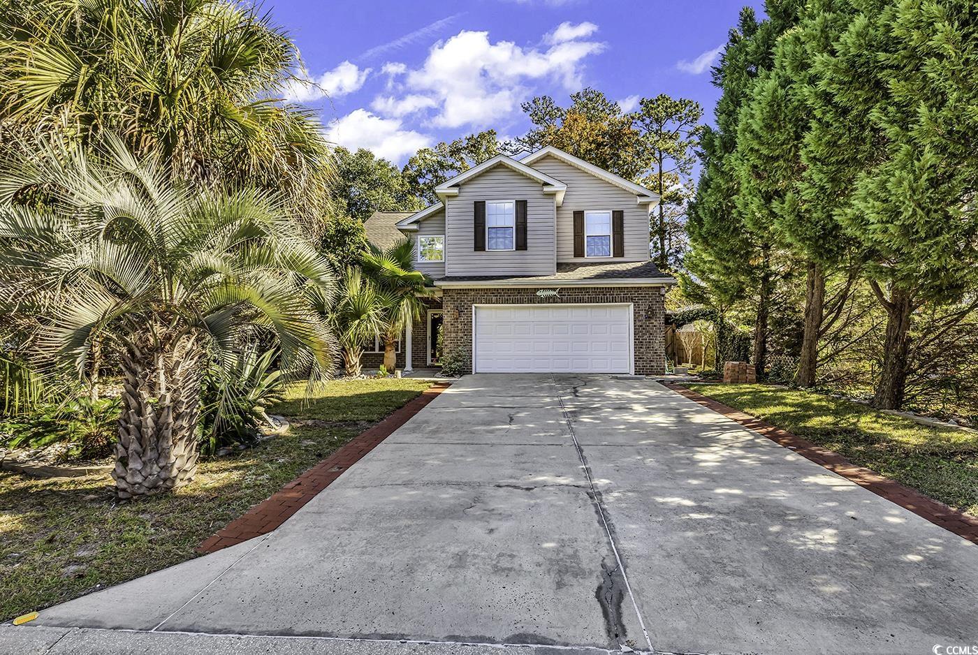 View of front facade featuring concrete driveway, brick siding, and an attached garage