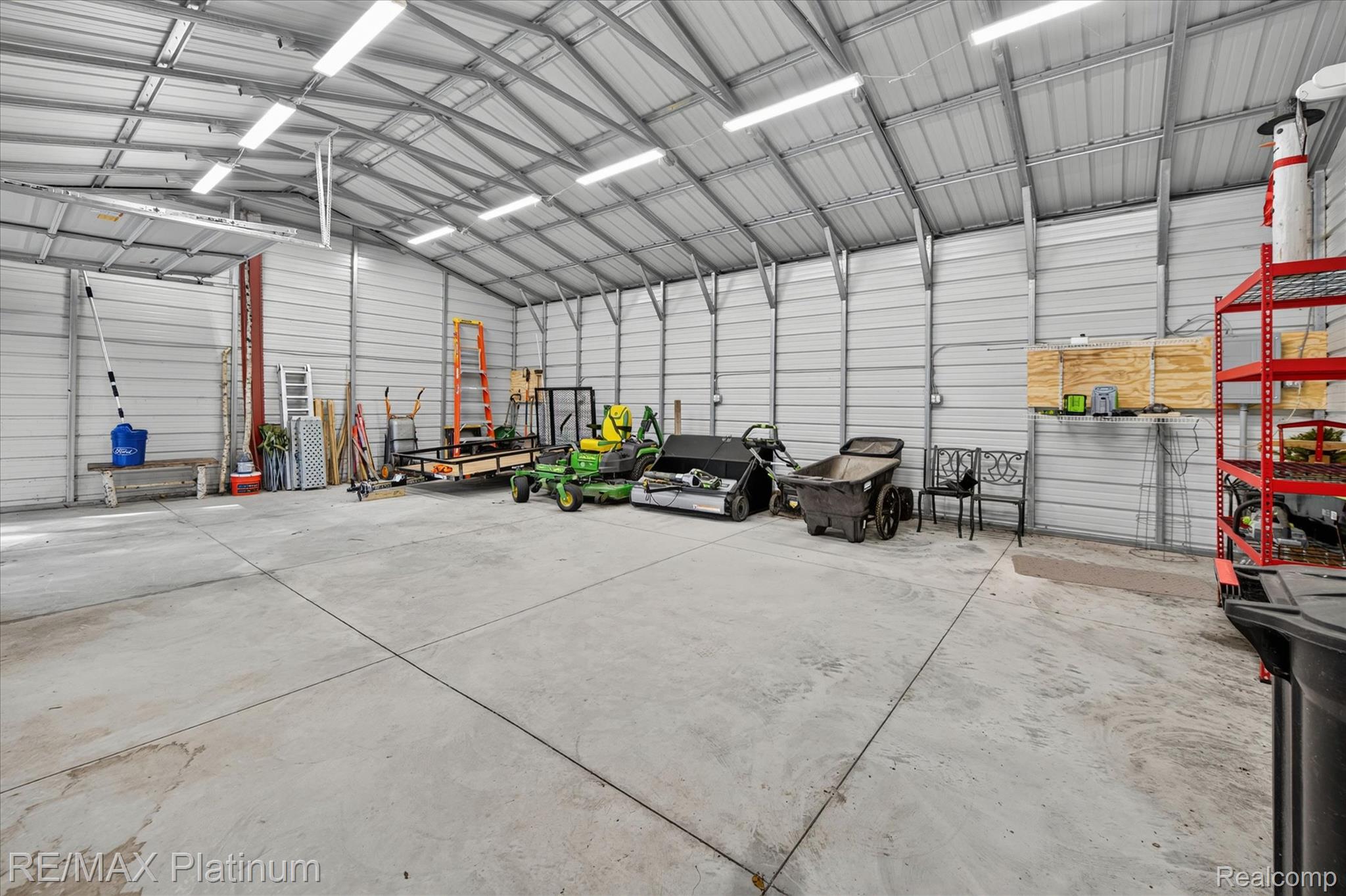 2676 Crooked Lake Road Howell, MI 48843 - Photo 46 of 60 Spacious metal building featuring a pitched metal roof, concrete flooring, exposed metal framing, and fluorescent overhead lighting