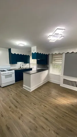 a view of kitchen and empty room with wooden floor