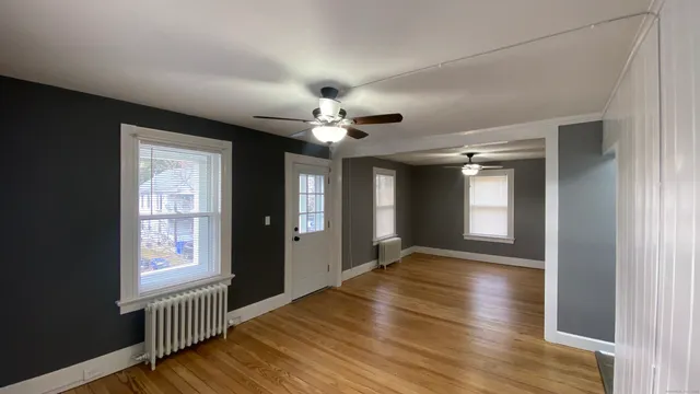 a view of an empty room with window and wooden floor