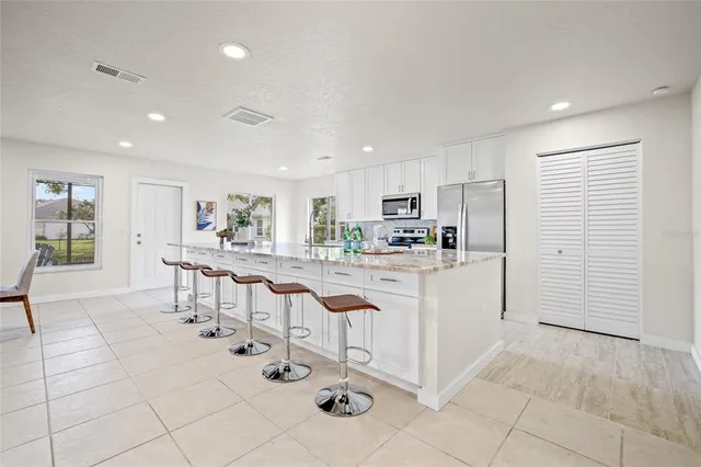 a kitchen with stainless steel appliances kitchen island granite countertop a refrigerator and cabinets