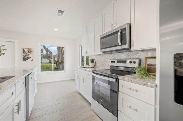 a kitchen with stainless steel appliances granite countertop a stove a sink and a microwave