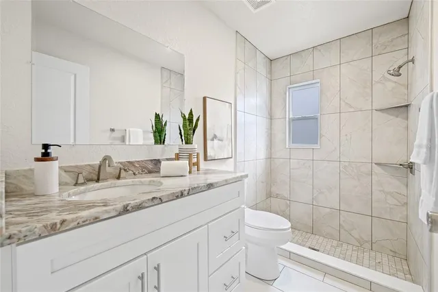 a bathroom with a granite countertop sink a toilet and shower