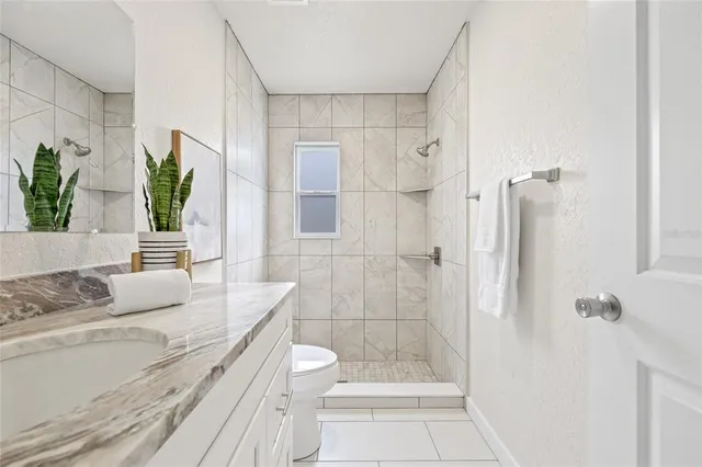 a bathroom with a granite countertop sink a toilet and shower