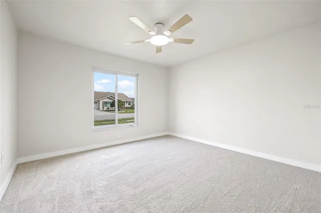 an empty room with windows and ceiling fan