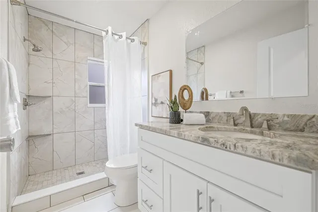 a bathroom with a granite countertop sink a toilet and shower