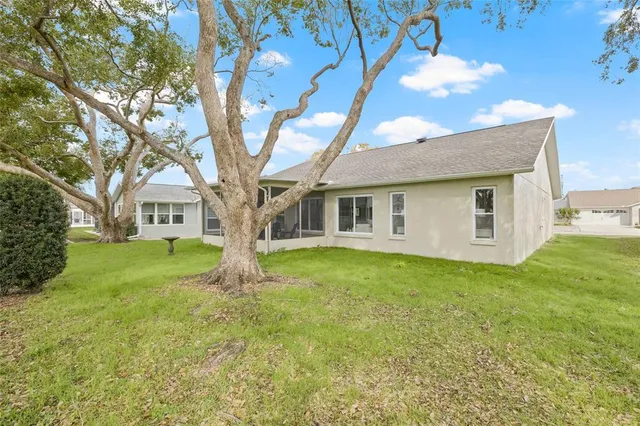 a large tree in front of a house with a garden