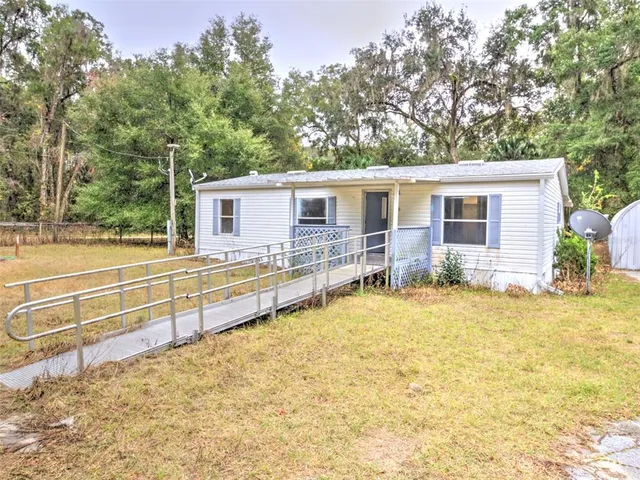 a view of house with backyard and trees in the background