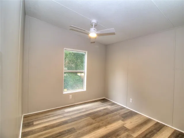 an empty room with a window and ceiling fan