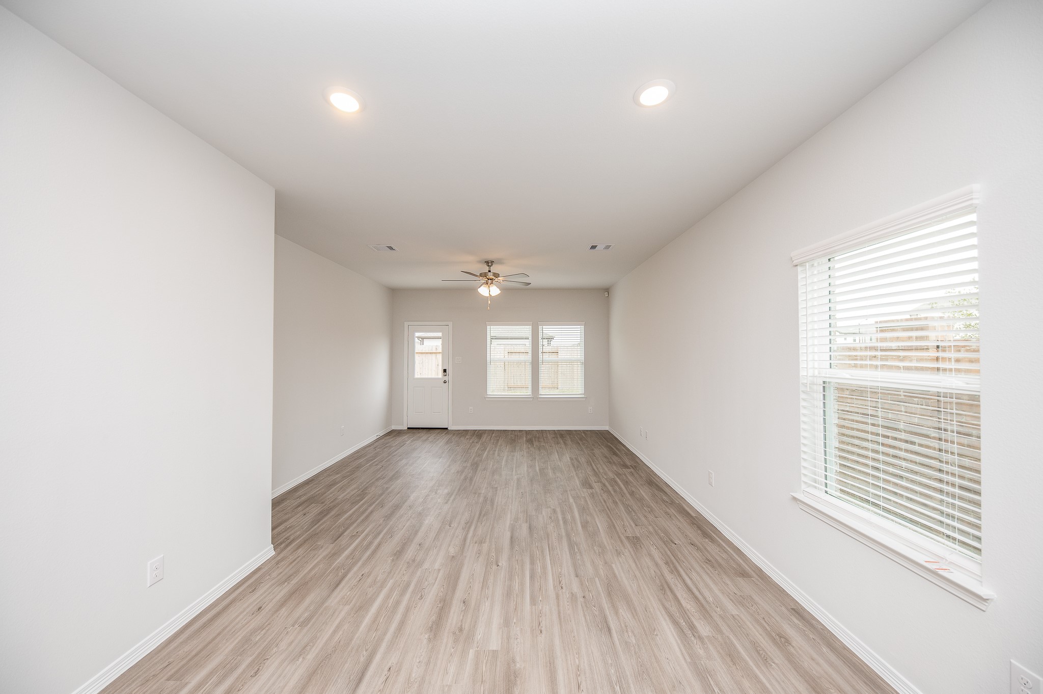 23302 Spring Genesis Lane Katy, TX 77493 - Photo 15 of 32 Bright and spacious room with light wood flooring, neutral walls, recessed lighting, and a ceiling fan. It features large windows and a glass door leading to the outside, providing ample natural light.