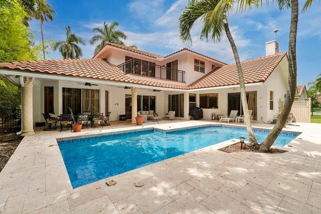 a view of a white house with a yard patio and swimming pool