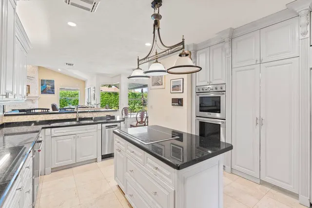 a kitchen with kitchen island a counter appliances a sink and cabinets