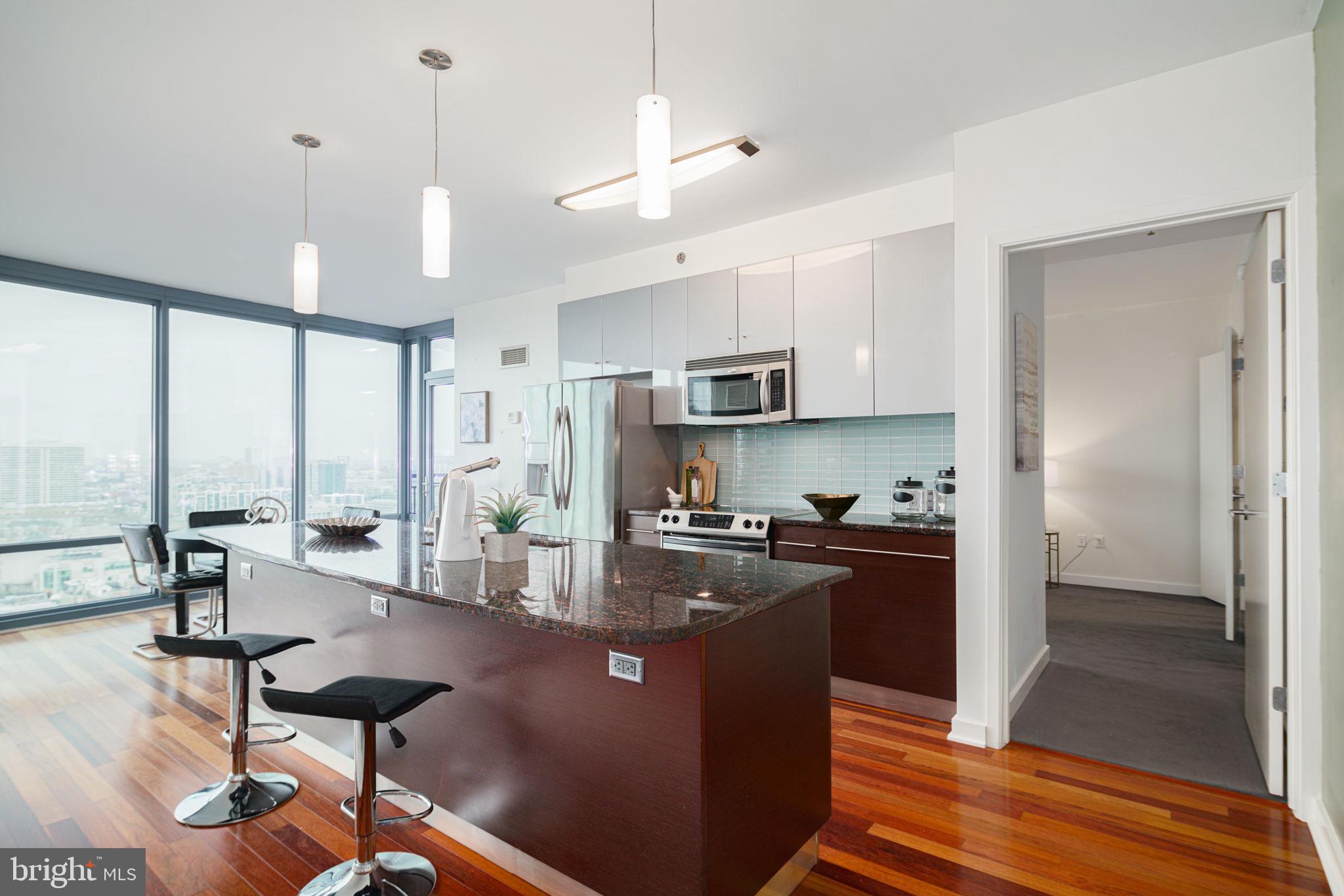 2101 Market Street, Unit 1901 Philadelphia, PA 19103 - Photo 6 of 25 a kitchen with stainless steel appliances granite countertop a refrigerator a stove a sink a dining table and chairs with wooden floor