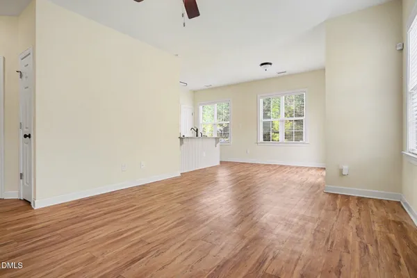 an empty room with wooden floor and windows