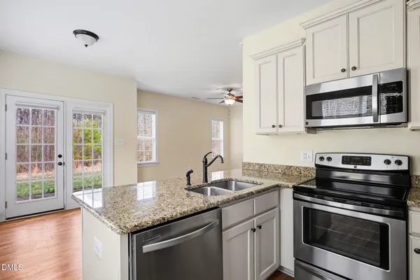 a kitchen with granite countertop a sink cabinets and stainless steel appliances