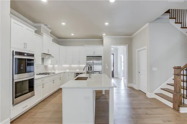 a kitchen with stainless steel appliances granite countertop a refrigerator a stove and a sink