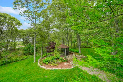 a view of a house with a big yard plants and large trees