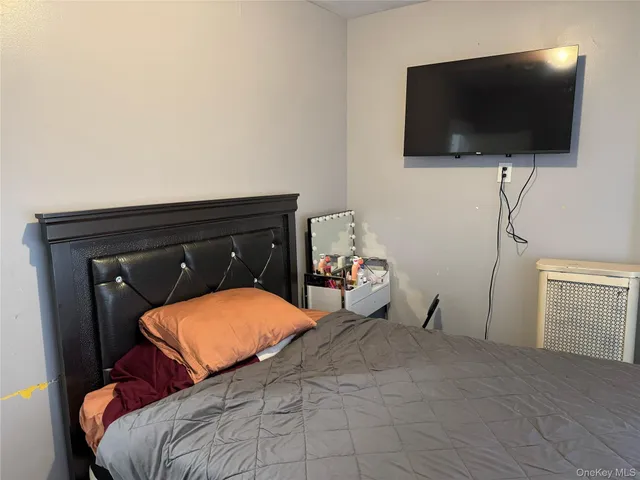 a bedroom with a bed and a flat tv screen on dresser