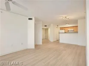 a view of a big room with wooden floor and a kitchen