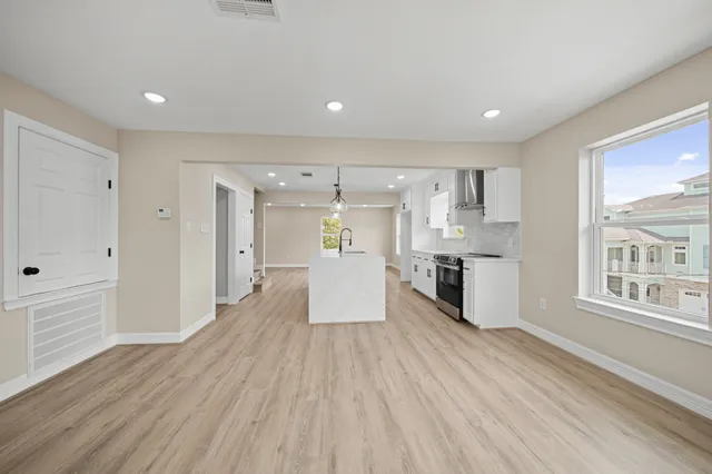 a large kitchen with stainless steel appliances a large counter top a wooden floors and a large window