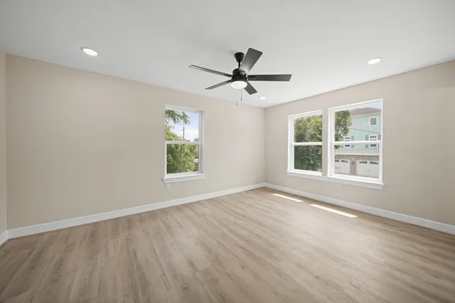 a view of empty room with wooden floor and fan
