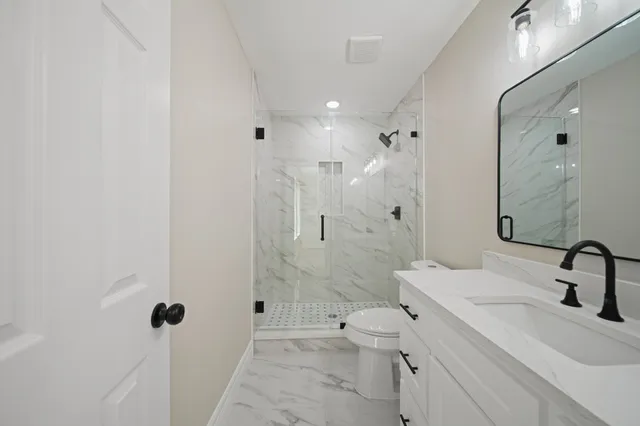 a bathroom with a sink a toilet and shower