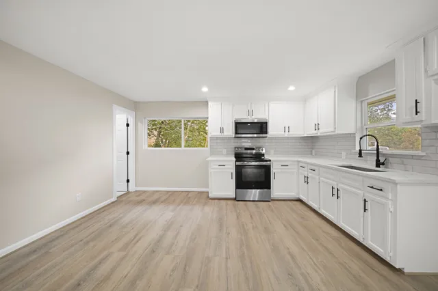 a kitchen with granite countertop a sink cabinets and stainless steel appliances