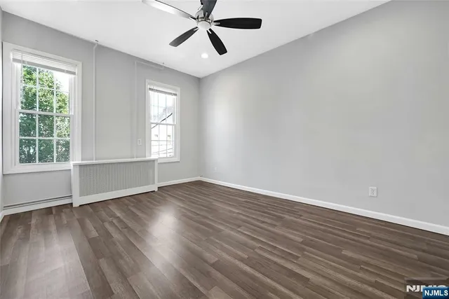 an empty room with wooden floor fan and windows