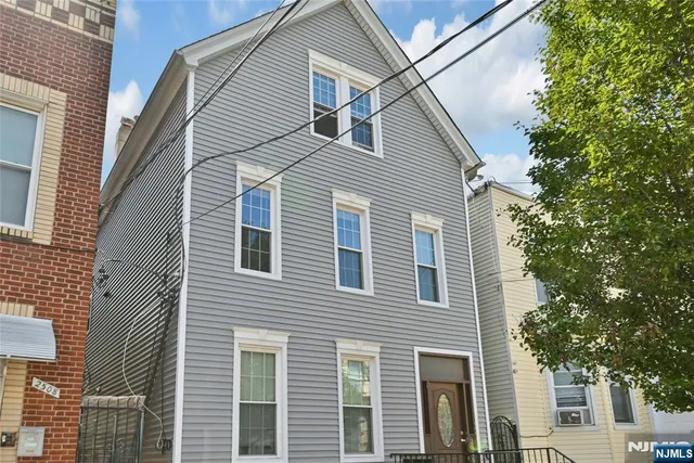 a front view of a house with a tree