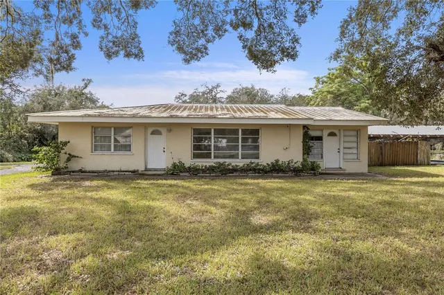 a view of a yard in front of a house with a large tree