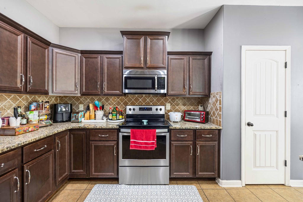 4936 Brightstar Lane Columbus, GA 31907 - Photo 11 of 42 a kitchen with stainless steel appliances granite countertop a stove top oven a sink dishwasher and a refrigerator with wooden cabinets
