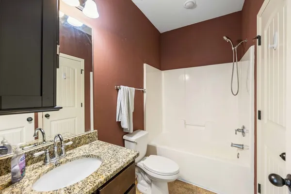 a bathroom with a granite countertop sink toilet and shower