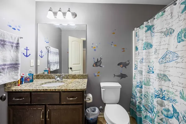 a bathroom with a granite countertop toilet sink and mirror
