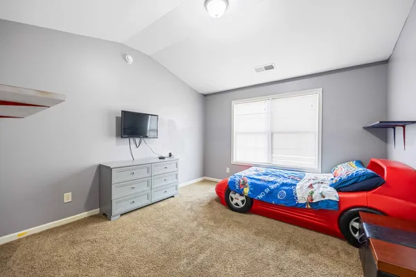 a bedroom with a bed and flat tv screen on the dresser