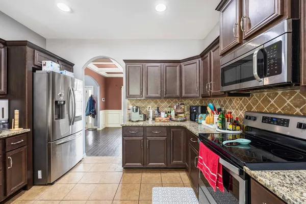 a kitchen with stainless steel appliances granite countertop a stove a sink dishwasher and a refrigerator with wooden cabinets