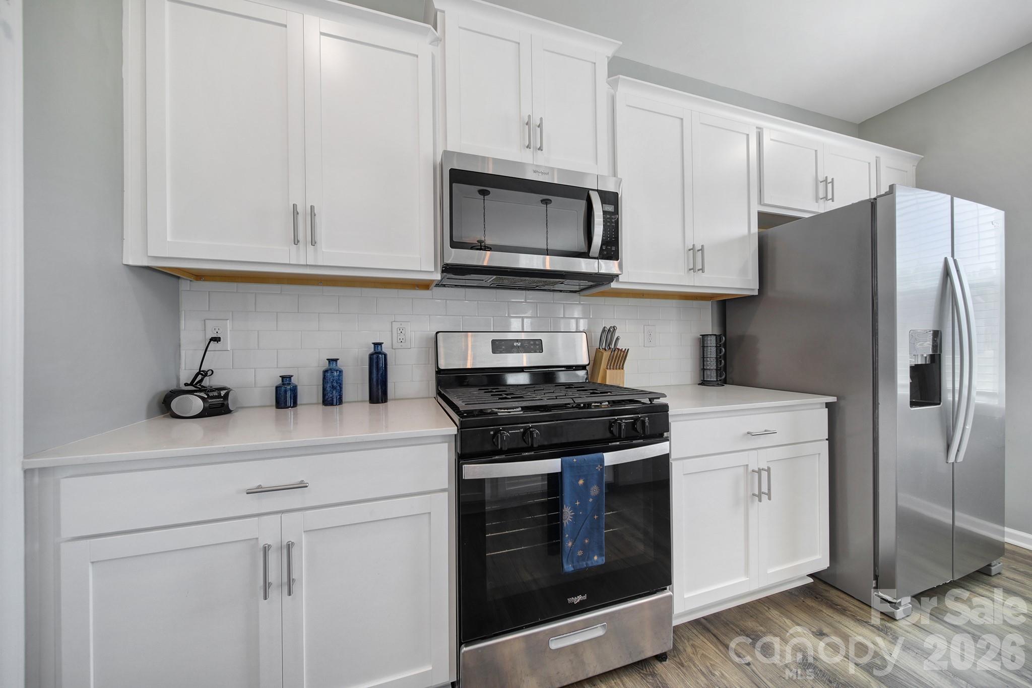 107 Spring Hall Court Troutman, NC 28166 - Photo 6 of 28 a kitchen with white cabinets and stainless steel appliances
