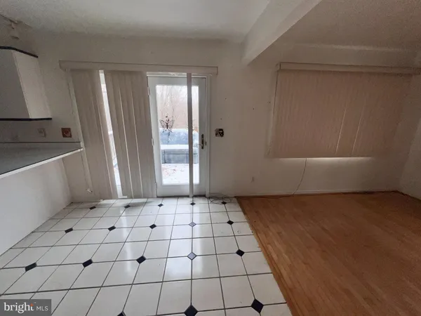 an empty room with wooden floor and windows with curtains