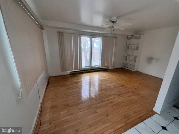 an empty room with chandelier fan and windows