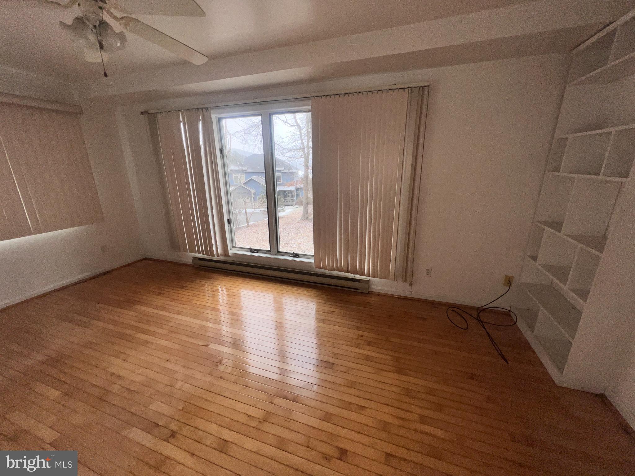 198 Pysell Road McHenry, MD 21541 - Photo 21 of 47 an empty room with wooden floor and windows with curtains