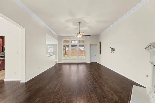 an empty room with wooden floor chandelier and windows