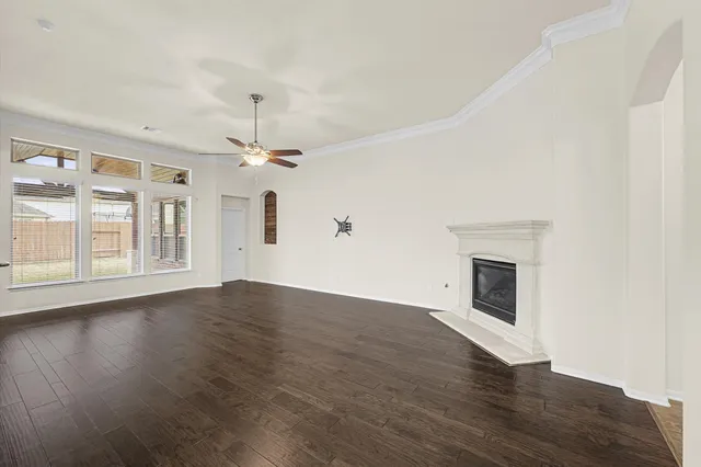a view of an empty room with wooden floor fireplace and a window