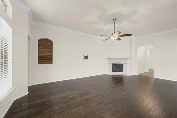 an empty room with wooden floor chandelier fan and windows