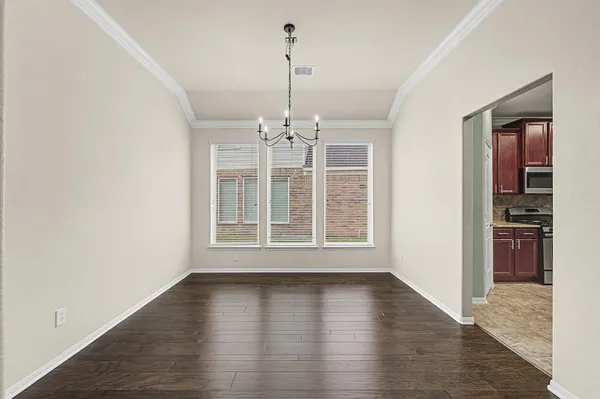 an empty room with wooden floor chandelier and windows