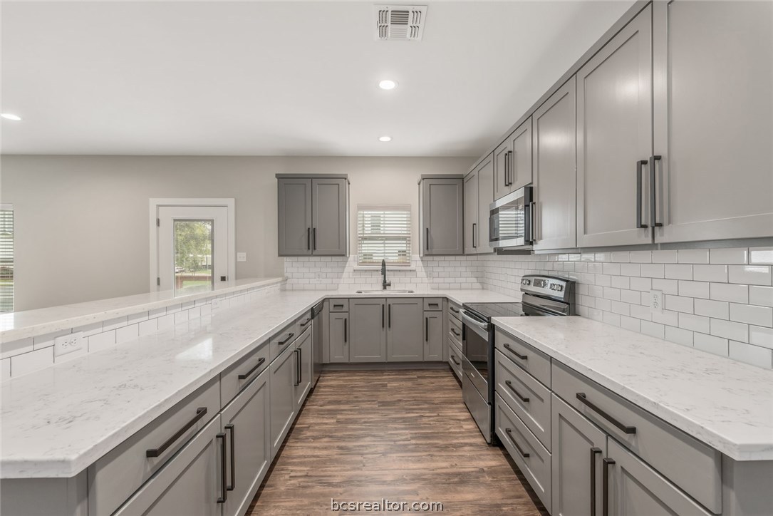 a large kitchen with stainless steel appliances lots of counter space sink and cabinets