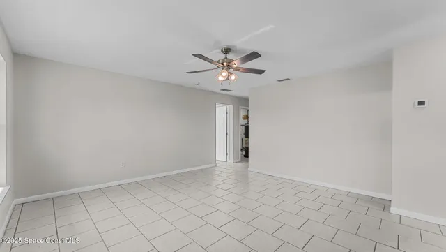 a view of an empty room and chandelier fan