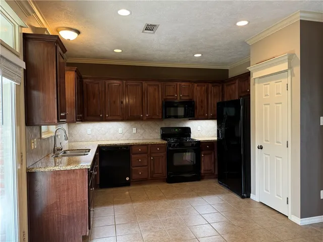 a kitchen with granite countertop wooden cabinets stainless steel appliances and a window