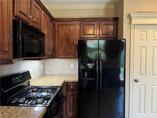 a kitchen with stainless steel appliances granite countertop wooden cabinets a stove top oven a sink and dishwasher