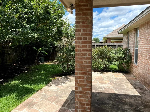 a view of a brick house with a small yard plants and large tree